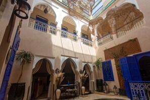 A multi-level courtyard with arches, a dining area, and blue doors. - Riad La Rose Orientale Marrakech (Marrakech)