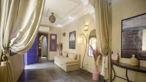 A hotel lobby with a sofa, decorative lamps, a painting, and a view of the outdoors.