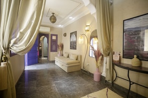 A hotel lobby with a sofa, decorative lamps, a painting, and a view of the outdoors. - Riad La Rose Orientale Marrakech (Marrakech)