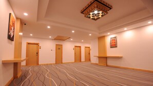 A hotel lobby with a patterned carpet, wooden doors, and a decorative ceiling light fixture. - Thimphu Central Hotel (Thimphu)
