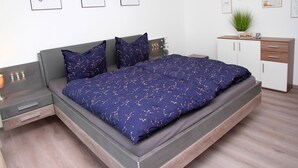 Un dormitorio moderno con cama, mesitas de noche, cómoda y decoración en la pared.