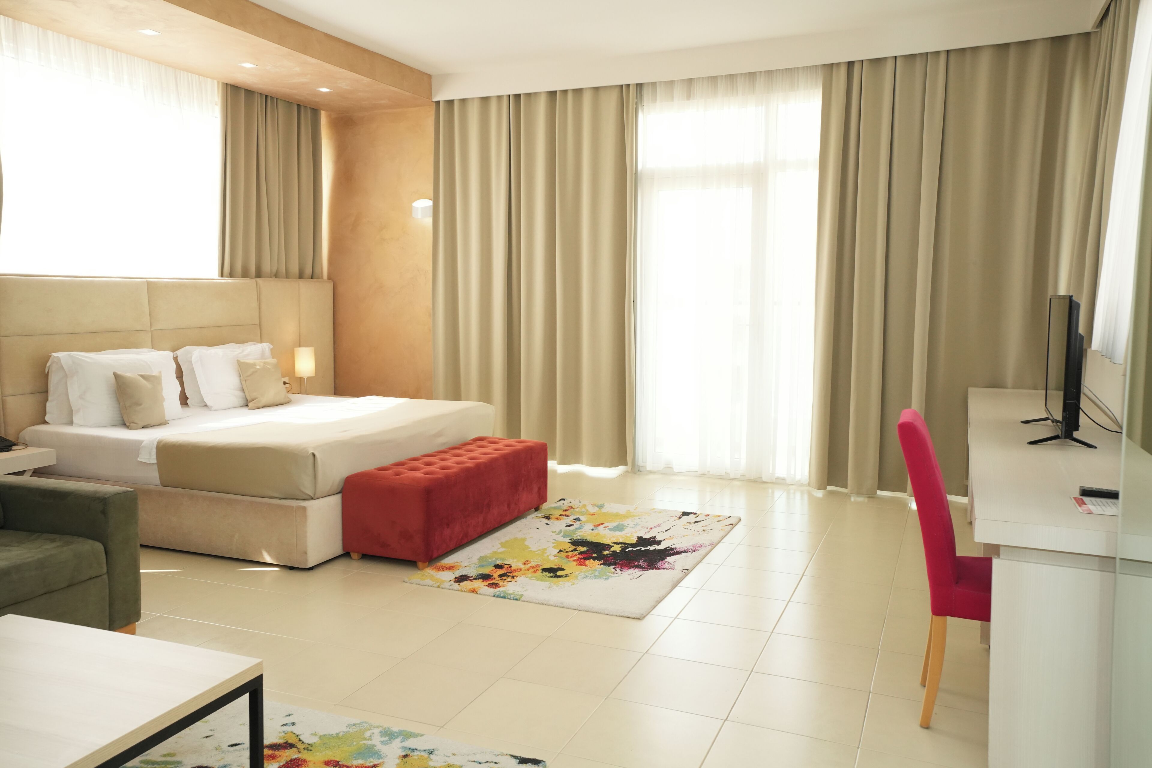 A hotel room with a bed, a desk, a chair, and a TV.