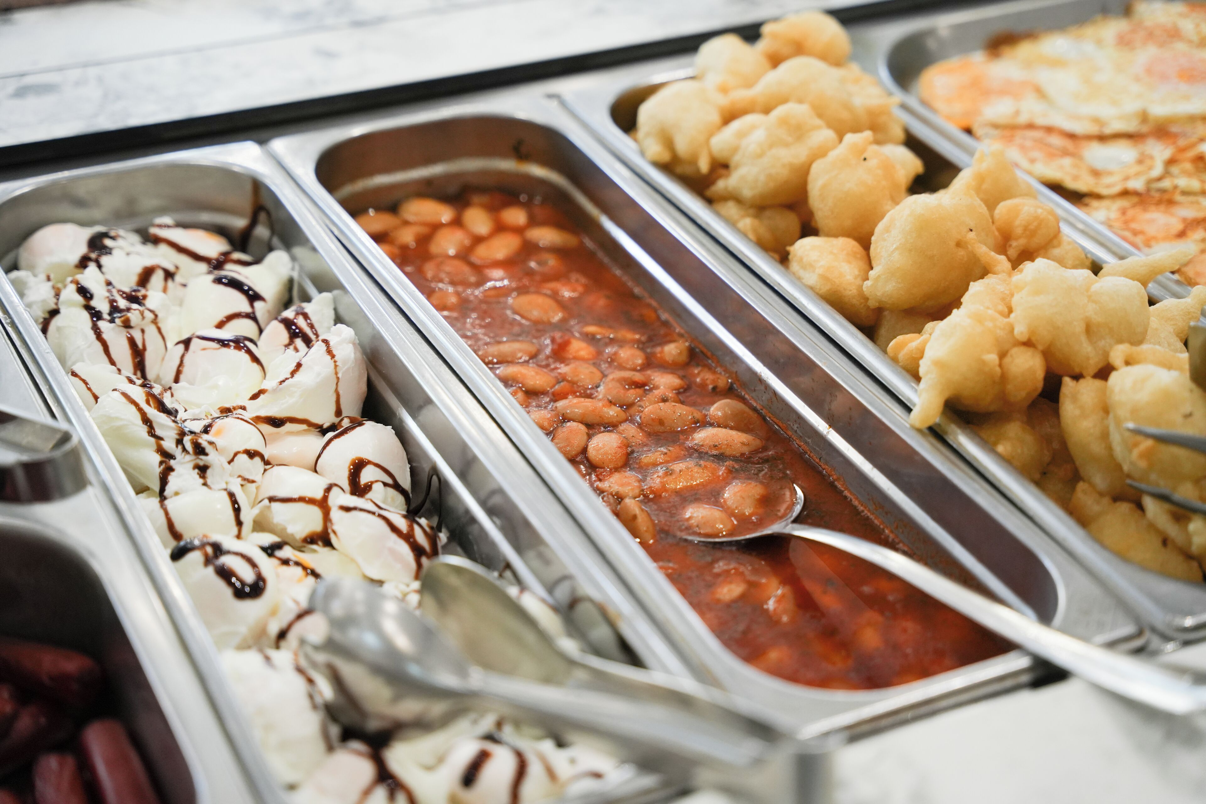 A buffet with various food options including ice cream, beans, and fried items.
