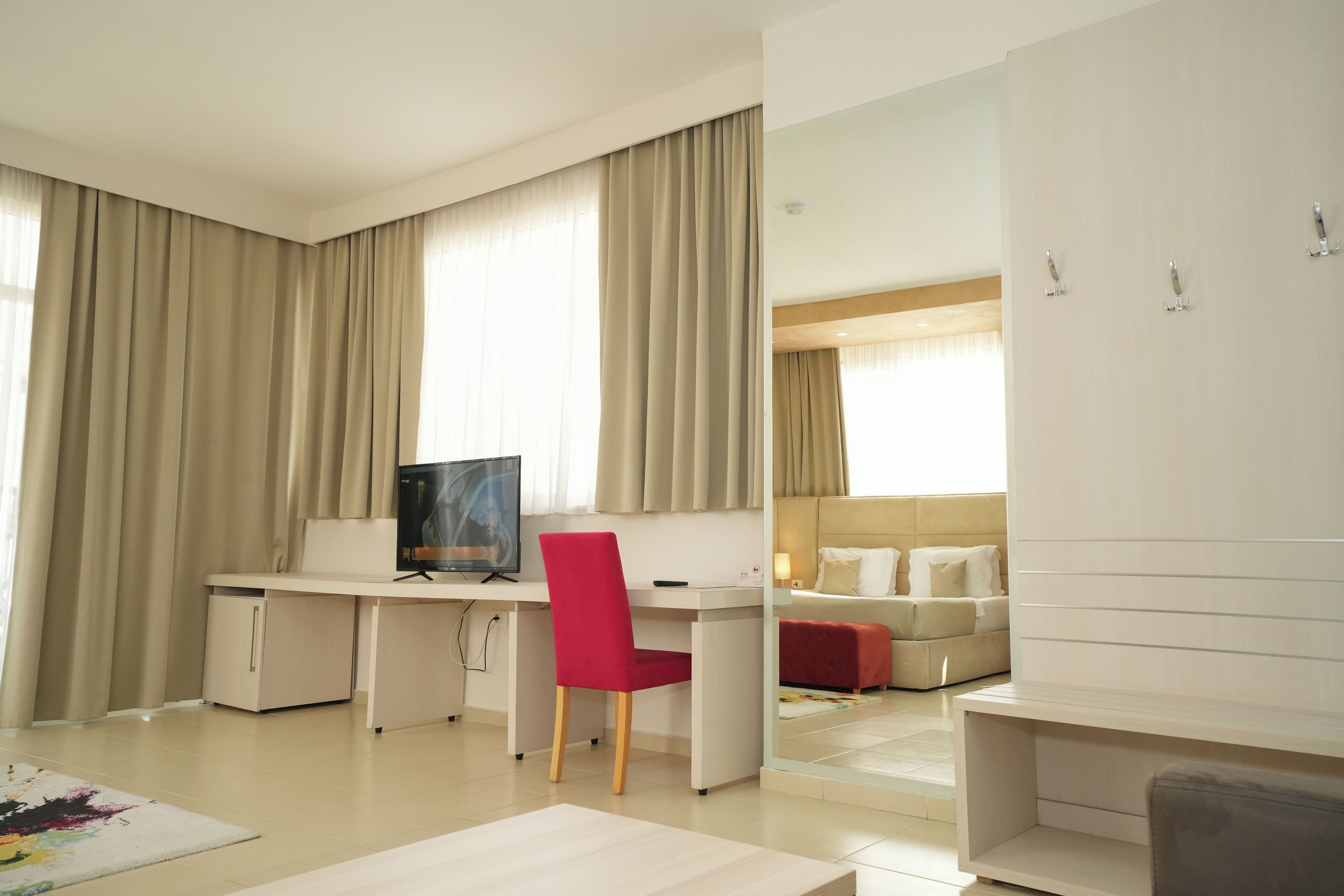 Une chambre d’hôtel moderne équipée d’un bureau, d’une chaise, d’une télévision et d’un lit avec une tête de lit.
