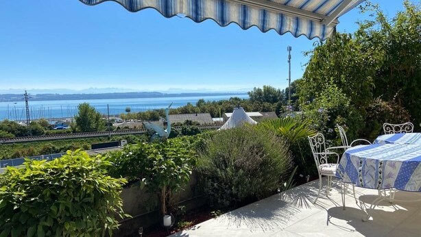 Una terraza con vista al mar, zona de estar cubierta y plantas en macetas.