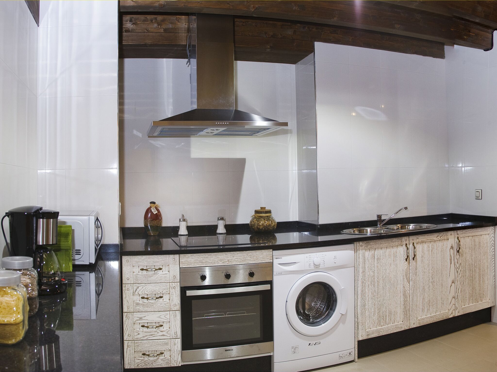 Una cocina moderna equipada con horno empotrado, microondas y lavadora.