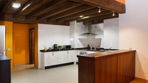 A modern kitchen with white cabinets, a wooden island, and a stainless steel range hood. - La Casa del Vino (Fermoselle)