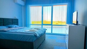 A hotel room with a bed, a desk, and a window with blinds. - Ubis hotel (Rodopi)