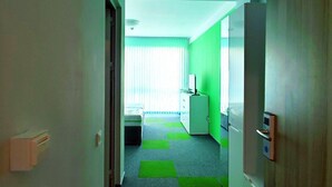 A hallway with a bed, a desk, and a green wall. - Ubis hotel (Rodopi)
