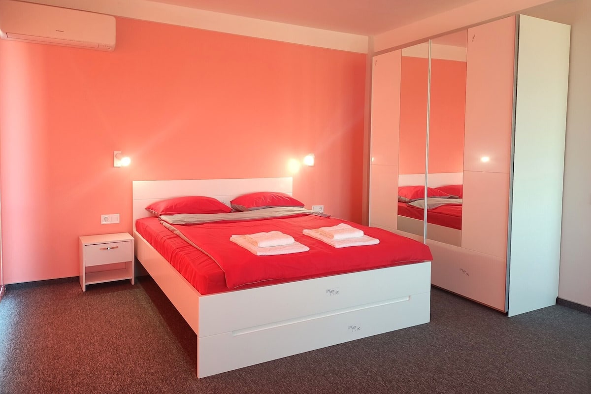 A bedroom with a bed, bedside tables, a wardrobe, and a mirror.
