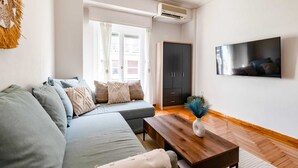 Un salon moderne avec un canapé, une table basse en bois et un téléviseur fixé au mur.