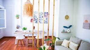 A modern living room with a wooden dining table, white chairs, a grey sofa, and various plants. - Acropolis Rooftop Monastiraki. (Athina)