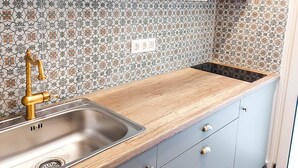 A kitchen with white cabinets, a wooden countertop, a stainless steel sink, and patterned backsplash tiles. - Acropolis Rooftop Monastiraki. (Athina)