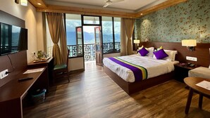 Ein Hotelzimmer mit Bett, Schreibtisch, Stuhl und einem Balkon mit Bergblick.
