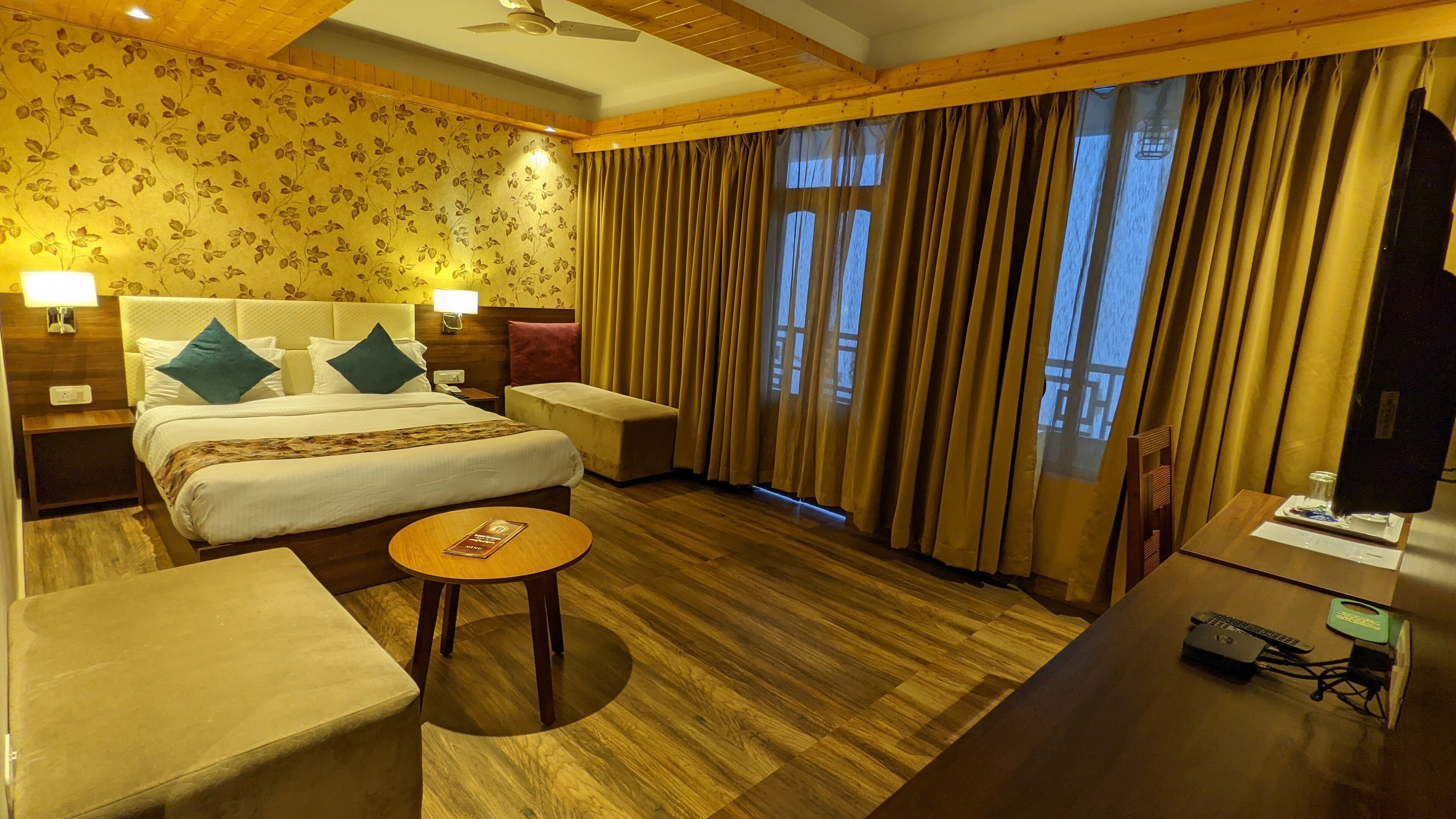 Une chambre d’hôtel comprenant un lit, des tables de chevet, un bureau, une chaise et une vue sur l’extérieur grâce à de grandes fenêtres.