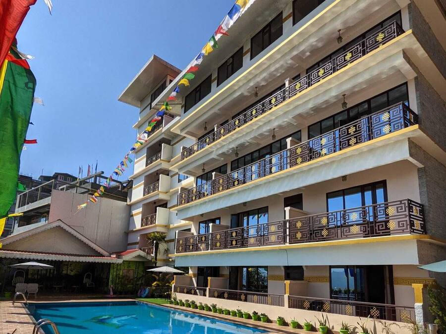 A multi-story hotel with balconies, a swimming pool, and flags.