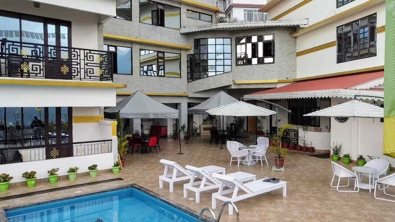 A multi-level outdoor pool area with lounge chairs, umbrellas, and potted plants.
