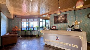 Ein Empfangsbereich mit Holzboden, einer Rezeption, einer Buddha-Statue und einem großen Fenster mit Aussicht.