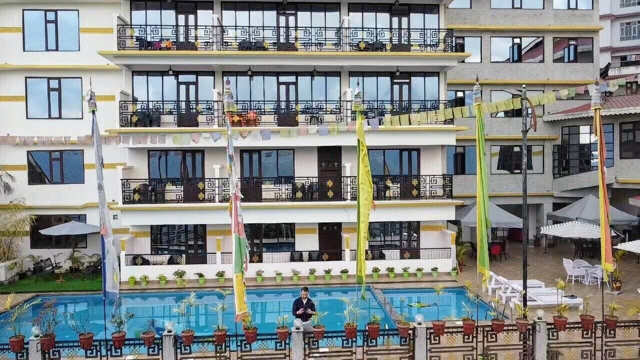 A multi-story hotel with balconies, a swimming pool, and outdoor seating areas.