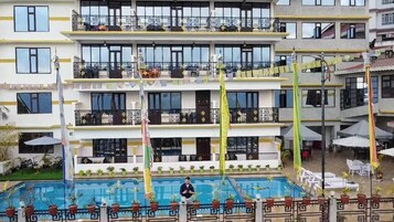 Un hotel a più piani con balconi, una piscina e zone relax all'aperto.
