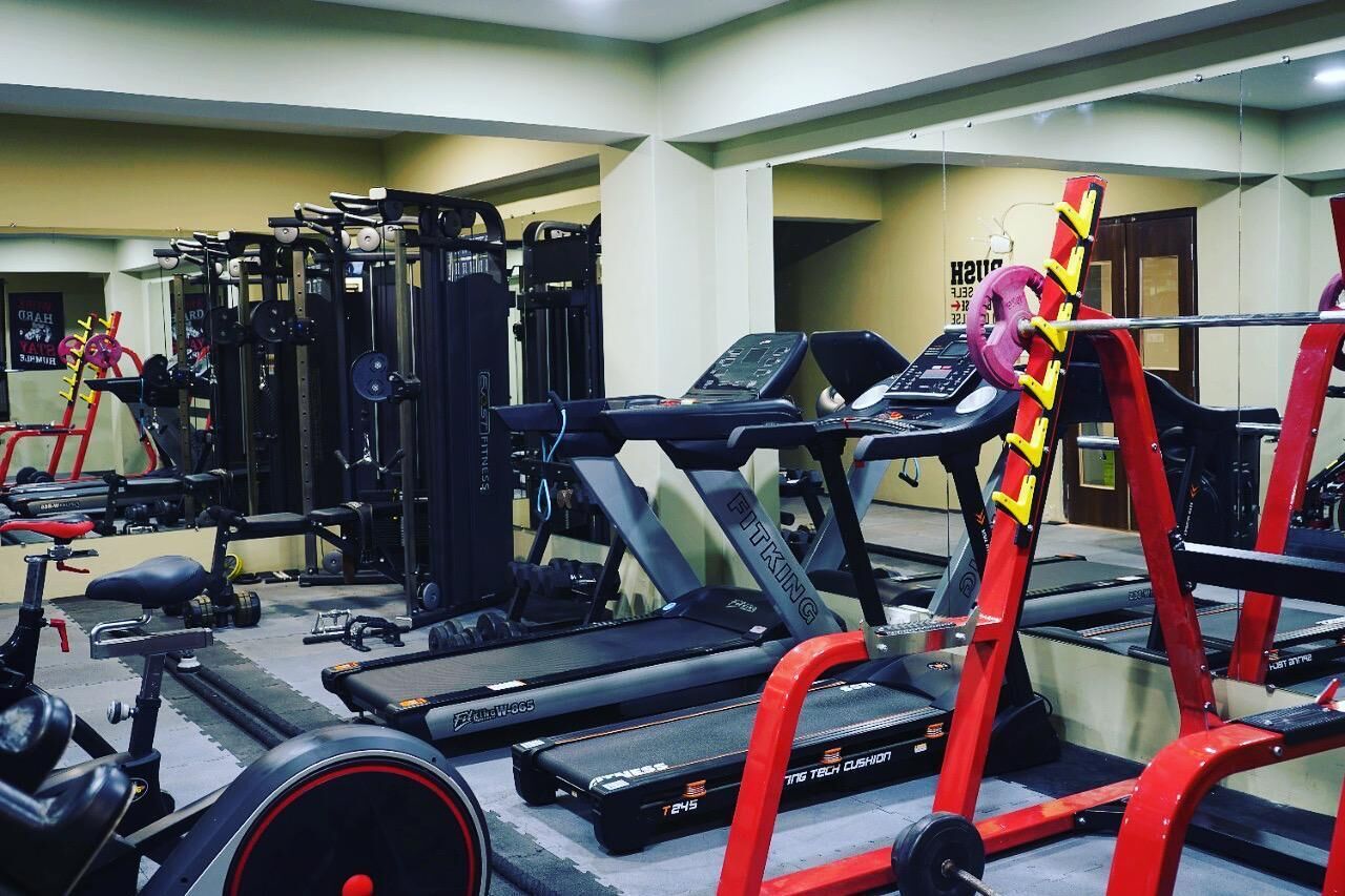 A gym with various exercise equipment including treadmills, weight machines, and free weights.