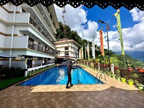 Ein Hotel mit Schwimmbad, mehreren Balkonen und Flaggen.