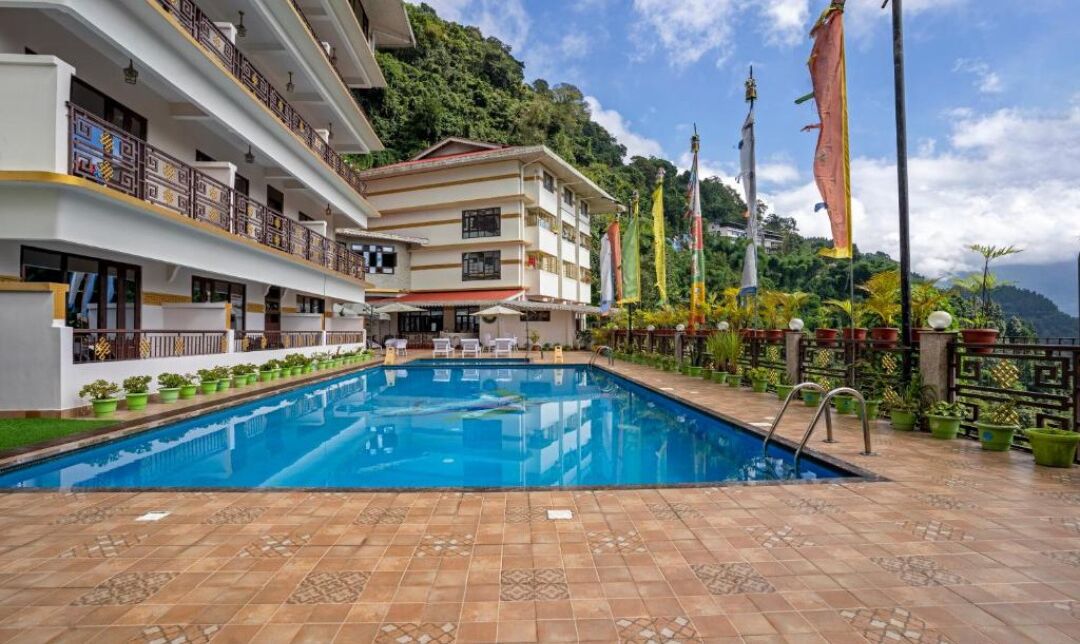 A hotel with a swimming pool, multiple balconies, and flags.