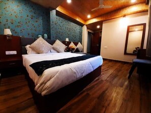 Ein Schlafzimmer mit Holzboden, einem Bett mit weißer Bettwäsche und einem Deckenventilator.