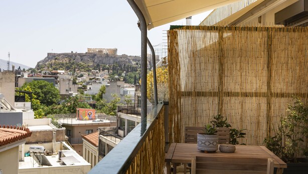 A balcony with a view of a historic building on a hill, a bamboo fence, and a table with potted plants. - Dls*apartment (Αθήνα)