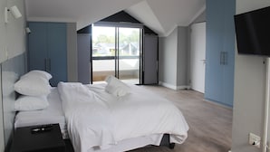A bedroom with a bed, a TV, and a sliding glass door to the outside. - Pearl Valley Golf Lodge - Loadshedding f (Paarl)