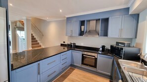 A modern kitchen with blue cabinets, a black countertop, stainless steel appliances, and a built-in oven. - Pearl Valley Golf Lodge - Loadshedding f (Paarl)
