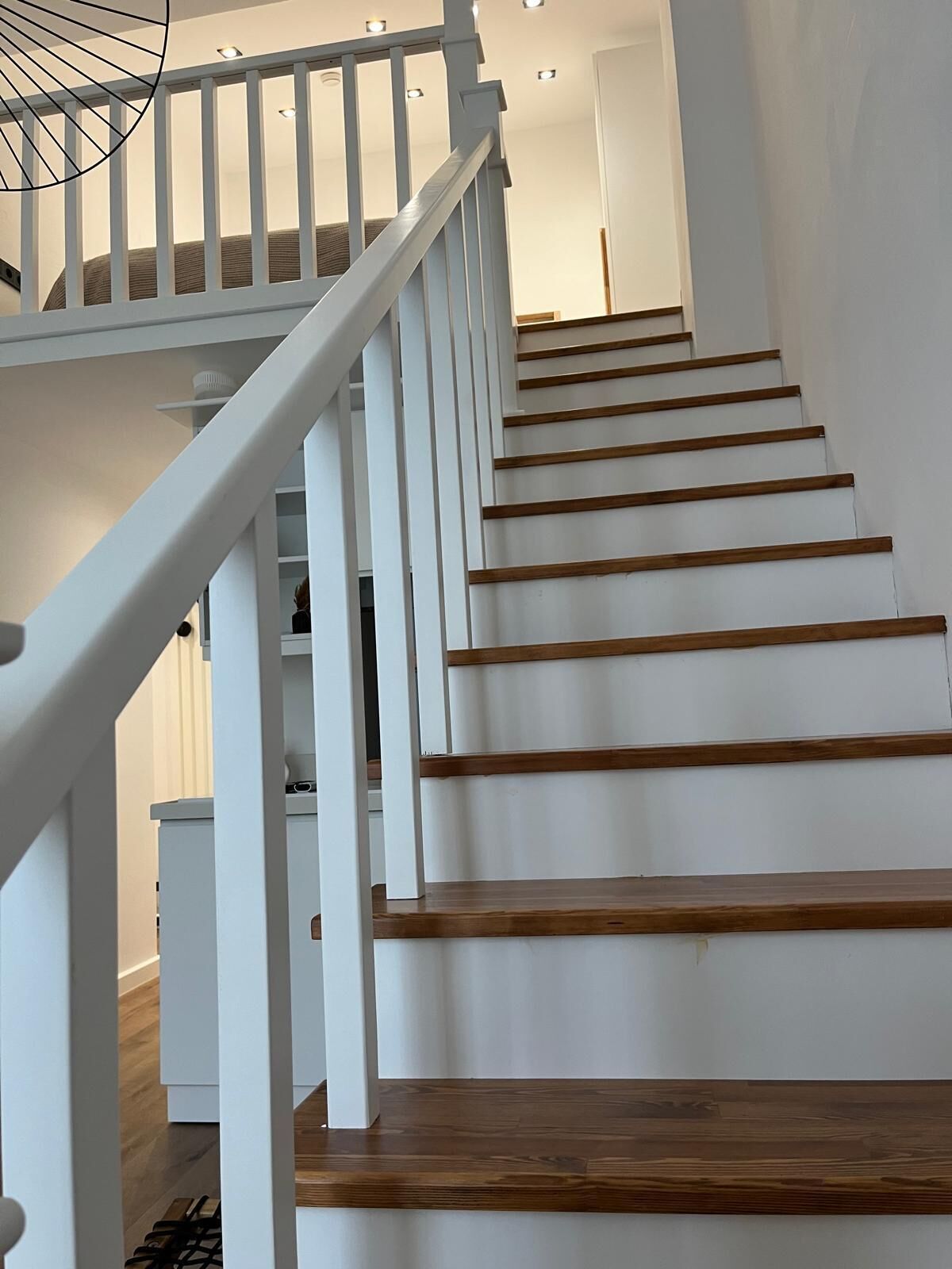 A staircase with white railings and wooden steps leading to a landing.