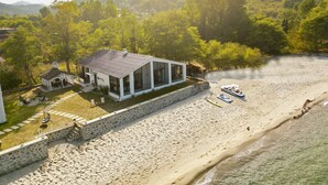 A coastal property with a stone wall, a covered patio, and a beach with boats. - Mehmetbey Çaka (Persembe)