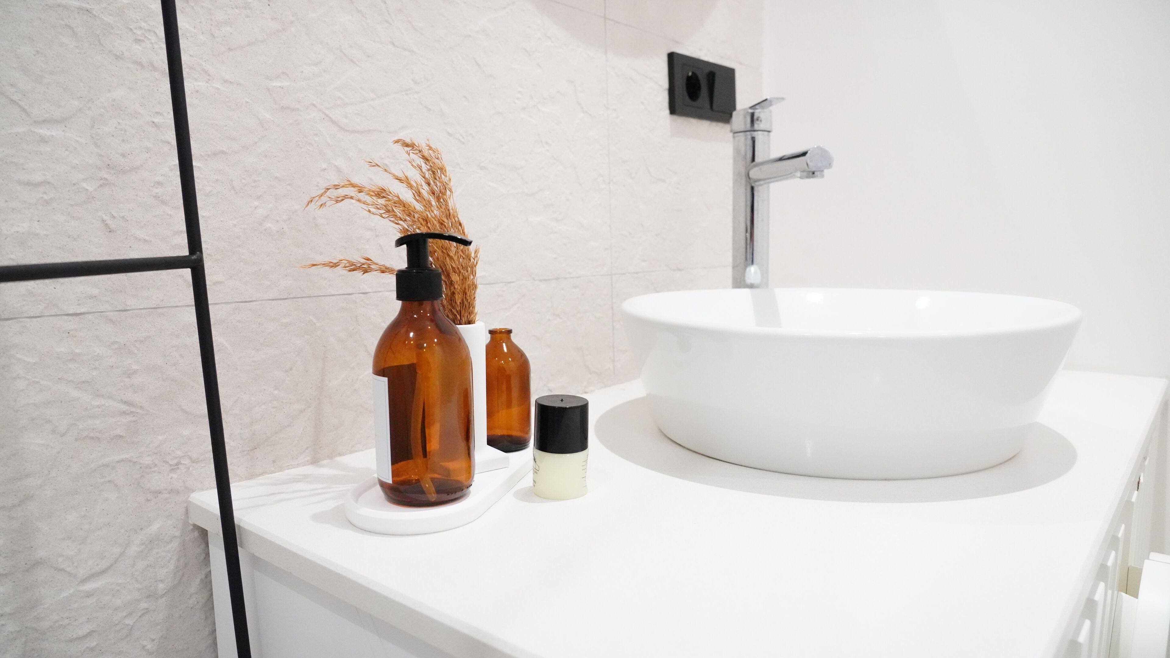 A bathroom with a white sink, a black faucet, and a white countertop.