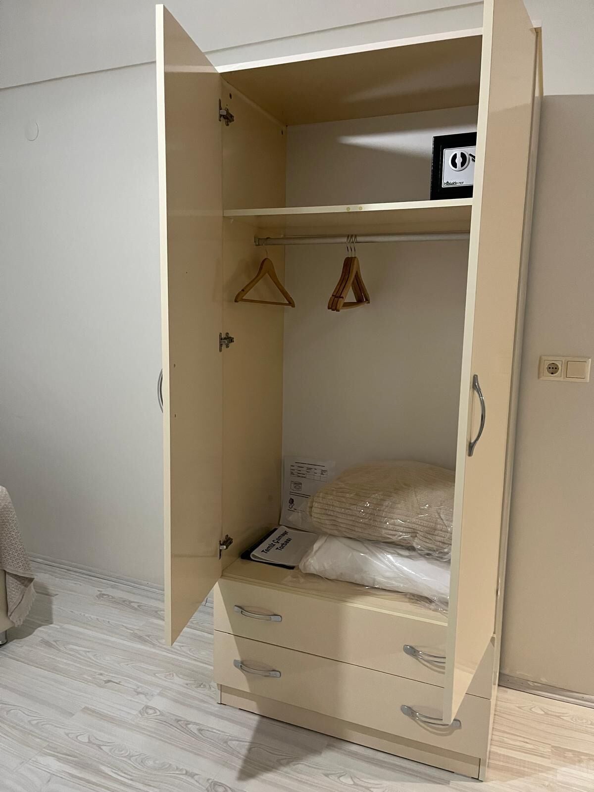 A beige wardrobe with a hanging rod, two drawers, and a shelf.