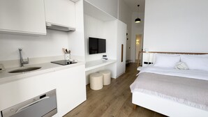 A modern, compact hotel room with a kitchenette, a bed, and a TV. - Mehmetbey Çaka (Persembe)