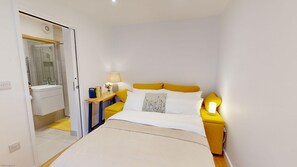 Cozy retreat with a neatly made bed, bedside table, and mirror.