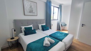 A double bed with teal bedding, a bedside lamp, and a wall-mounted artwork. - Vista Mar - AC, Parking and Pool (Funchal)
