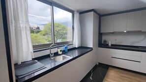 A modern kitchen with a large window, a sink, and a countertop. - Vista Mar - AC, Parking and Pool (Funchal)