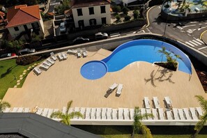 A swimming pool with a unique design, surrounded by lounge chairs and palm trees.