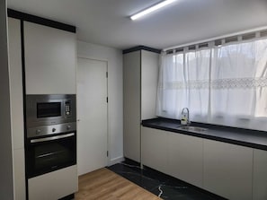 A compact kitchen with a microwave, oven, and a sink.