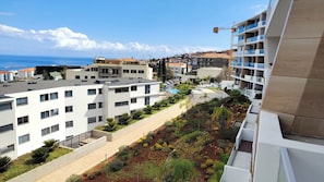 A residential area with modern buildings, a clear sky, and a view of the sea. - Vista Mar - AC, Parking and Pool (Funchal)