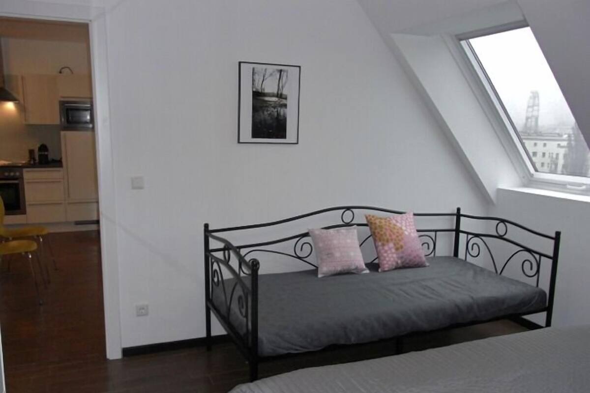 A bedroom with a bed, a window, and a view of a cityscape.