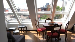 A room with a skylight, a round table with chairs, and a sofa. - Kunsthaus Apartments (Vienna)