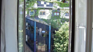 A view from a window with a view of a building with multiple windows and balconies, surrounded by greenery. - Kunsthaus Apartments (Vienna)
