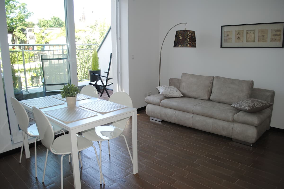 A living room with a white table, chairs, a beige sofa, and a potted plant.