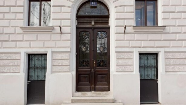 A building with a symmetrical facade, featuring a central arched entrance with a dark wooden door, flanked by two smaller doors. - Kunsthaus Apartments (Vienna)