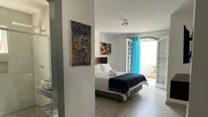 A spacious bedroom with a large bed, a walk-in closet, and a bathroom with a shower. - Hotel Boutique Casa Arte Cabore (Paraty)