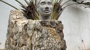 A stone planter with a head sculpture surrounded by large banana leaves. - Hotel Boutique Casa Arte Cabore (Paraty)