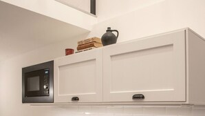 Eine moderne Küche mit weißen Schränken, einer schwarzen Spüle, einer eingebauten Mikrowelle und einer gefliesten Rückwand.